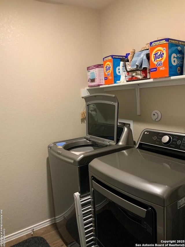 laundry area featuring baseboards, laundry area, wood finished floors, and washer and dryer