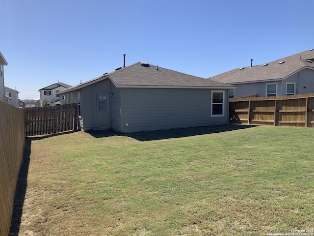 rear view of property featuring a fenced backyard and a yard