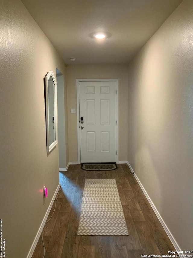 doorway featuring baseboards and wood finished floors