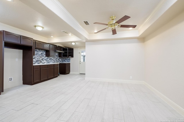 kitchen featuring dark brown cabinetry, visible vents, decorative backsplash, a tray ceiling, and light countertops