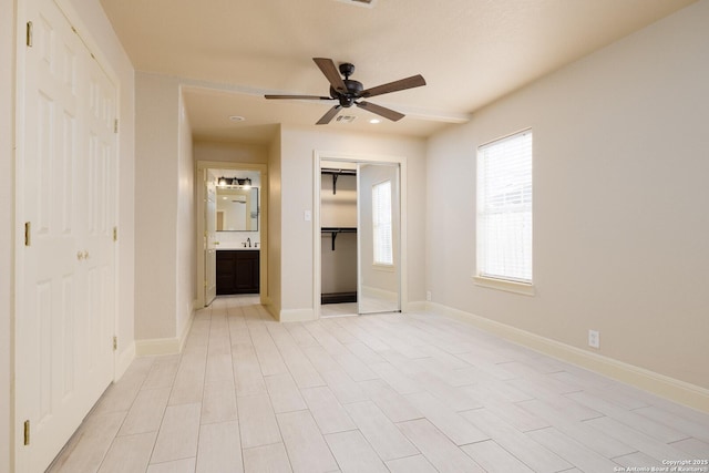 unfurnished bedroom with a closet, ceiling fan, ensuite bath, and baseboards