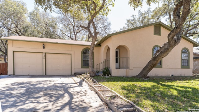 view of front of property with driveway, a front yard, an attached garage, and stucco siding