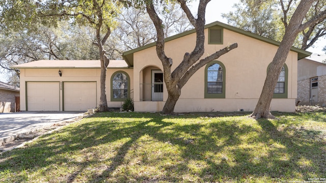 view of front facade with an attached garage, driveway, a front yard, and stucco siding