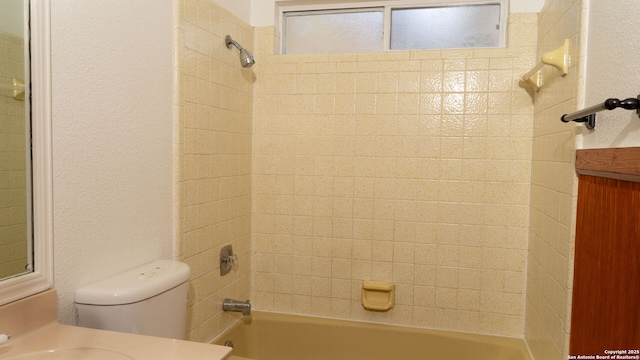 bathroom with toilet, a textured wall, shower / washtub combination, and vanity