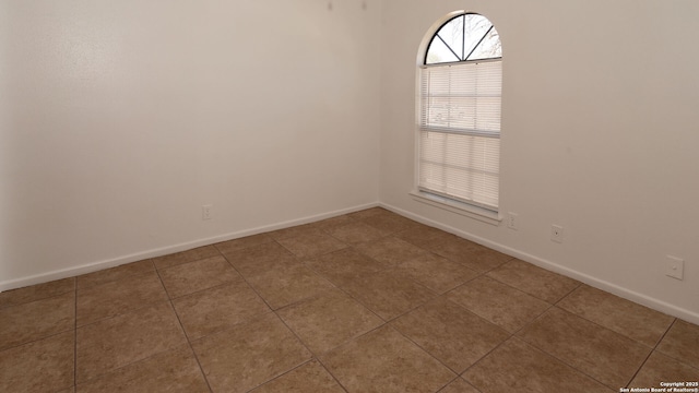 spare room featuring tile patterned flooring and baseboards