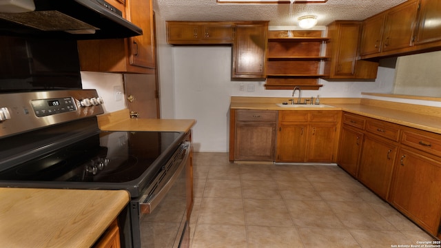 kitchen featuring under cabinet range hood, stainless steel electric range, brown cabinets, and a sink