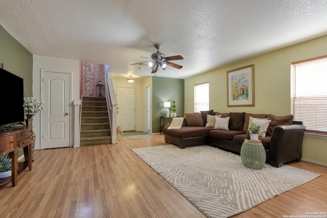 living room with plenty of natural light, ceiling fan, stairs, and light wood-style floors