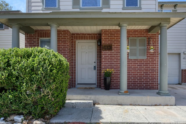 property entrance featuring a porch, brick siding, and a garage