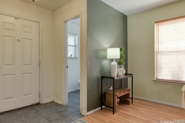 entrance foyer featuring a wealth of natural light, baseboards, wood finished floors, and a textured wall