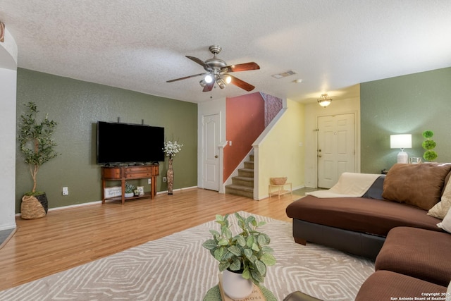 living area with stairway, a textured ceiling, visible vents, and wood finished floors