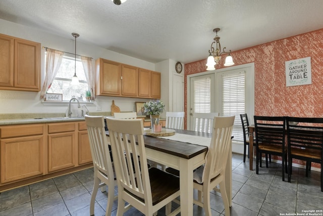 tiled dining space with wallpapered walls, a sink, and a textured ceiling