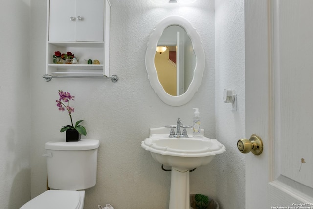 bathroom featuring toilet and a textured wall