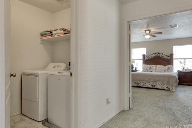 washroom with visible vents, light carpet, laundry area, washer and dryer, and a textured ceiling