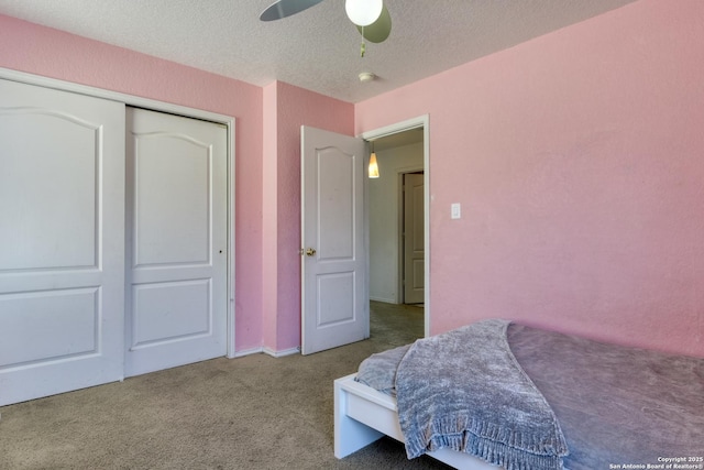 carpeted bedroom featuring ceiling fan, a closet, and a textured ceiling