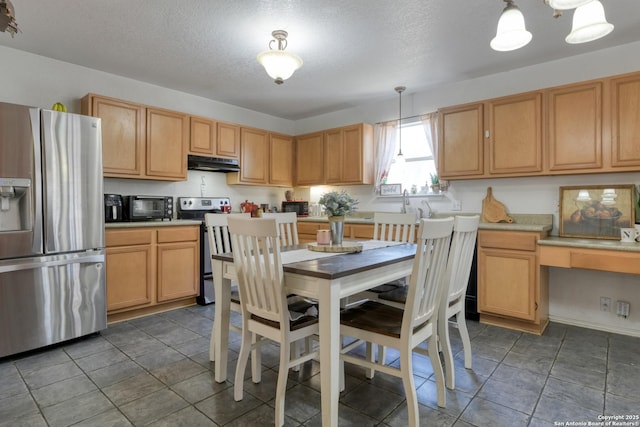 kitchen with built in study area, stainless steel appliances, light countertops, under cabinet range hood, and decorative light fixtures