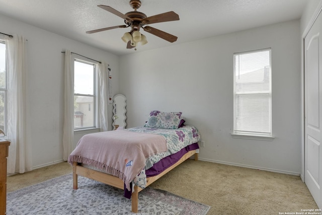 bedroom with a ceiling fan, baseboards, a textured ceiling, and carpet flooring