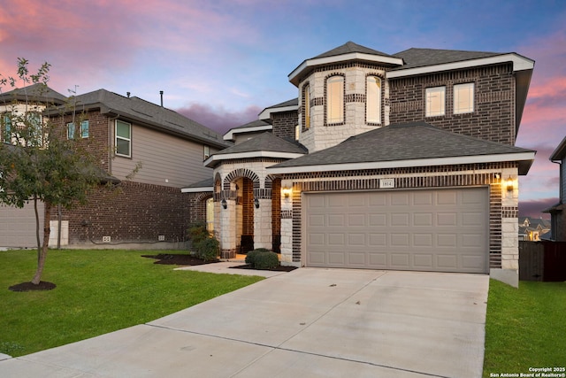 view of front facade with a shingled roof, concrete driveway, a lawn, and an attached garage