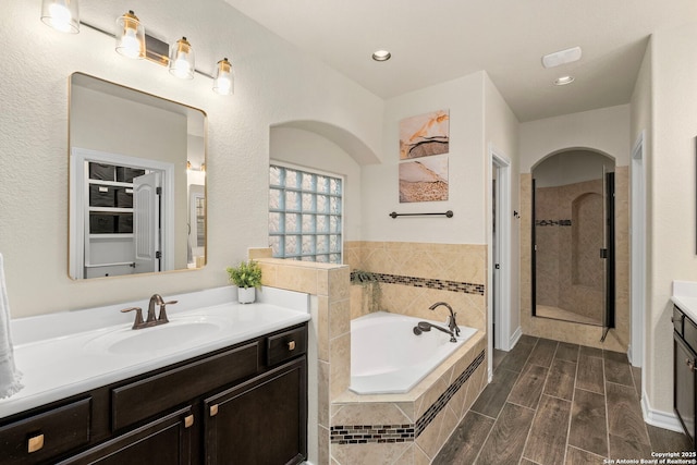 bathroom with a garden tub, recessed lighting, wood tiled floor, vanity, and a shower stall