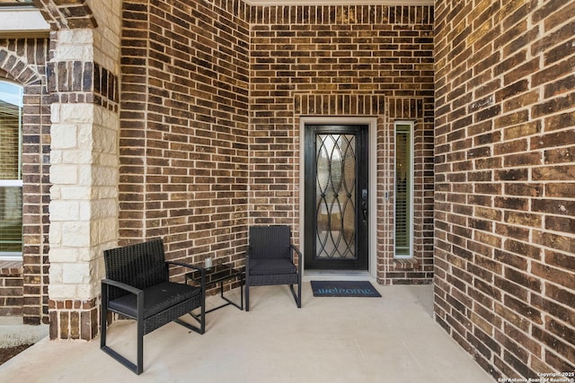 entrance to property featuring a patio area and brick siding