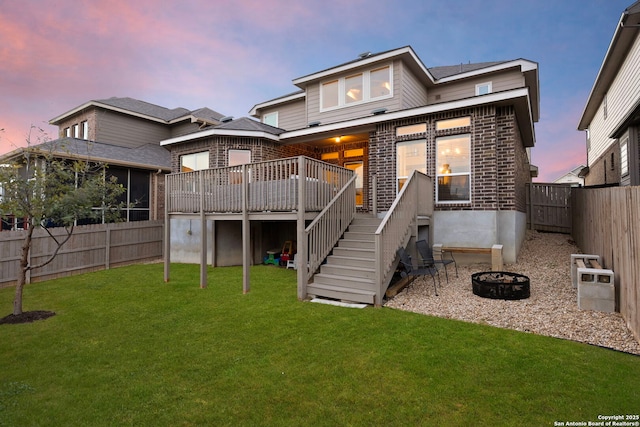 back of house with a deck, a fenced backyard, a fire pit, a lawn, and stairway