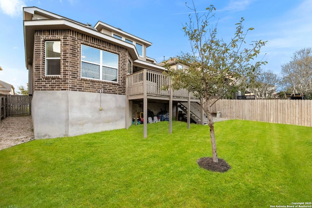 back of house featuring a fenced backyard, a lawn, stairway, and brick siding