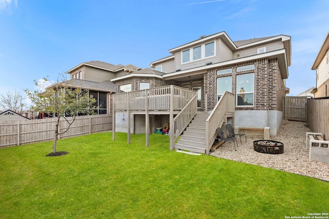 back of house featuring a yard, an outdoor fire pit, a deck, a fenced backyard, and stairs