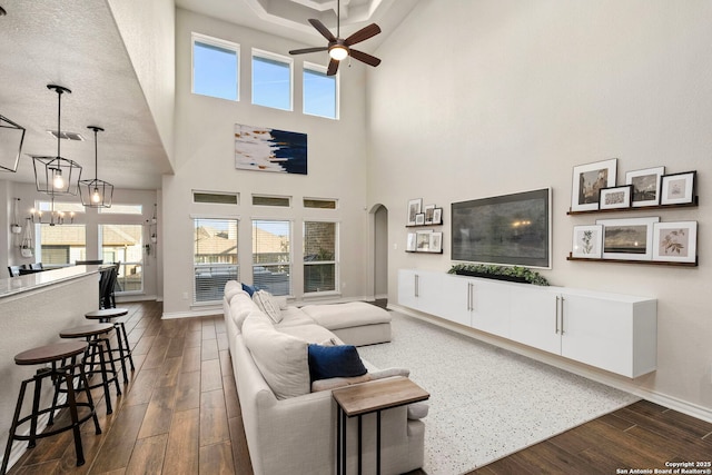 living area with arched walkways, baseboards, dark wood finished floors, and a healthy amount of sunlight