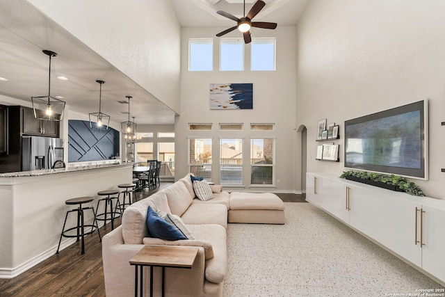 living area featuring a healthy amount of sunlight, ceiling fan, arched walkways, and wood finished floors