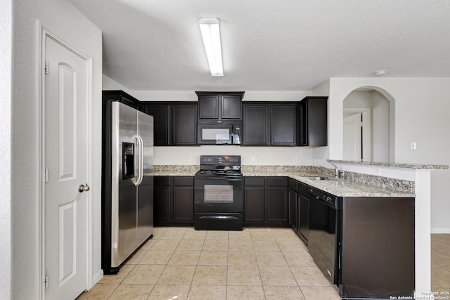 kitchen with light stone countertops, black appliances, a peninsula, and a sink