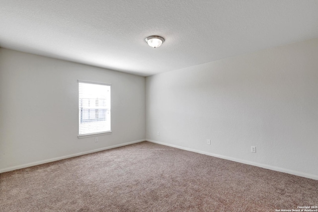 spare room with a textured ceiling, carpet floors, and baseboards