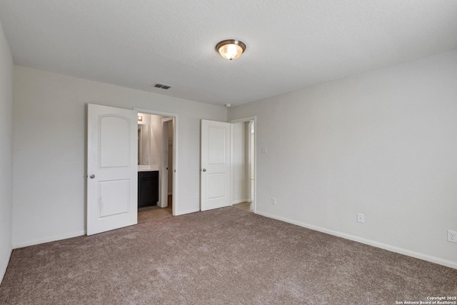 unfurnished bedroom featuring carpet, visible vents, a textured ceiling, and baseboards