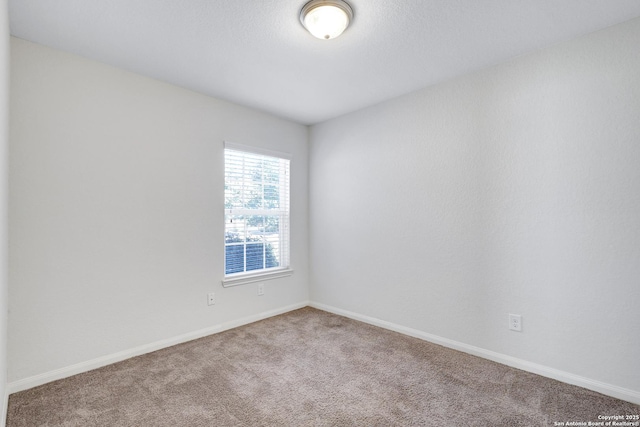 spare room featuring carpet and baseboards