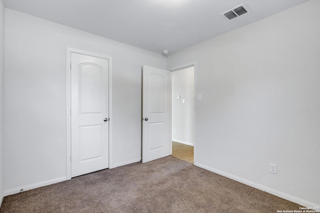 unfurnished bedroom featuring baseboards, visible vents, and carpet flooring