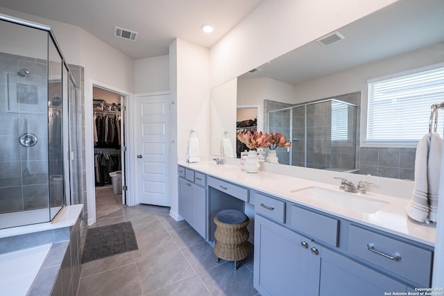 full bathroom featuring double vanity, visible vents, tile patterned flooring, a shower stall, and a sink