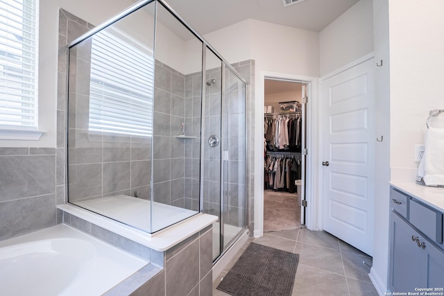 bathroom with a stall shower, a walk in closet, a garden tub, and tile patterned floors