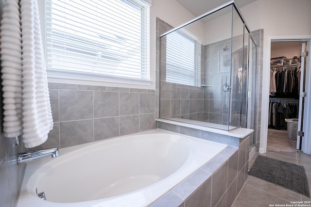 full bath with a shower stall, a spacious closet, a bath, and tile patterned floors