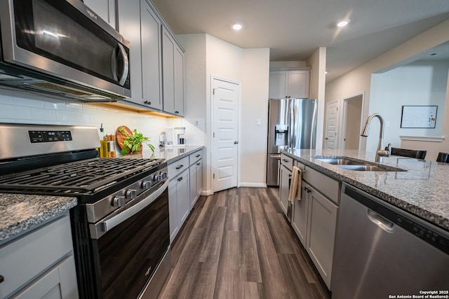 kitchen featuring stone counters, appliances with stainless steel finishes, a sink, and gray cabinetry