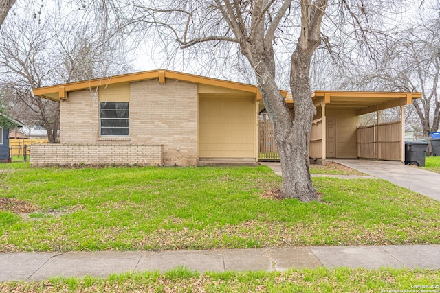 view of front facade with an attached carport, brick siding, driveway, and a front yard