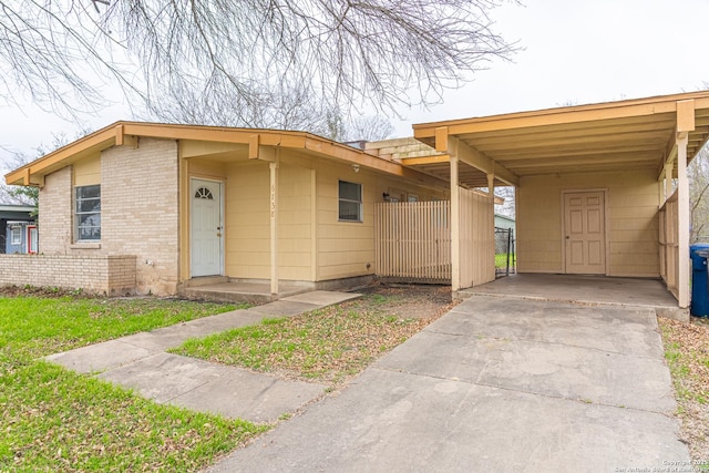 view of front of house featuring driveway, an attached carport, and brick siding