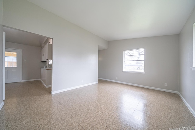 empty room featuring plenty of natural light, baseboards, and tile patterned floors