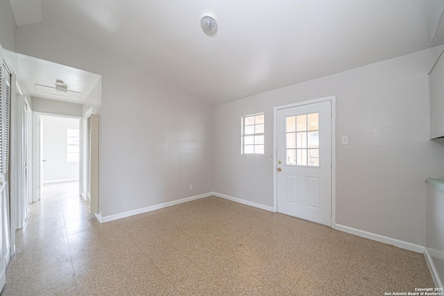 spare room with lofted ceiling, light floors, and baseboards