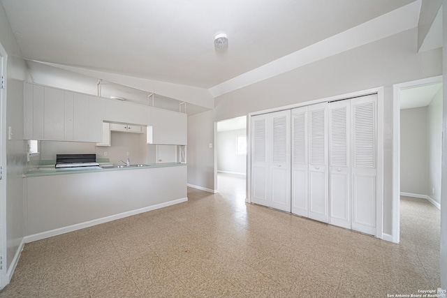 kitchen with lofted ceiling, light floors, a sink, and baseboards