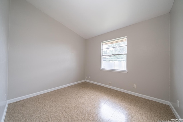 unfurnished room featuring lofted ceiling, baseboards, and tile patterned floors