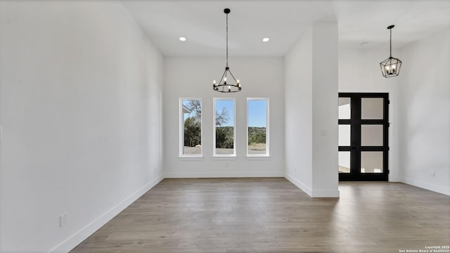 unfurnished dining area featuring recessed lighting, wood finished floors, baseboards, and an inviting chandelier