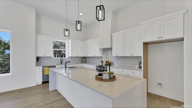 kitchen featuring light stone counters, a high ceiling, appliances with stainless steel finishes, white cabinetry, and an island with sink