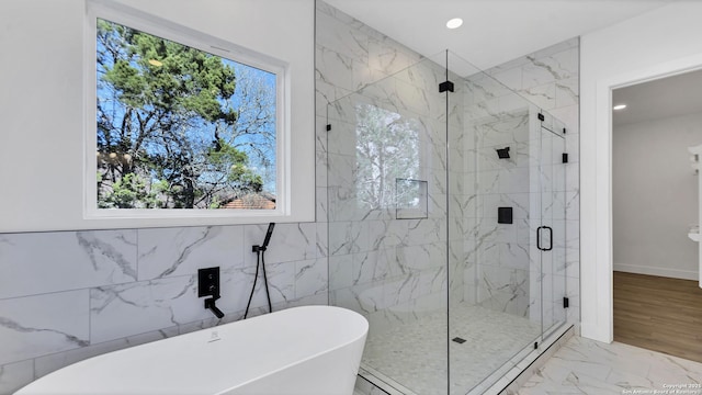 full bath with marble finish floor, a marble finish shower, a freestanding bath, and recessed lighting