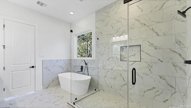 bathroom featuring a stall shower, visible vents, marble finish floor, a freestanding tub, and tile walls