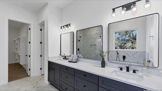 bathroom featuring double vanity, marble finish floor, a marble finish shower, and a sink