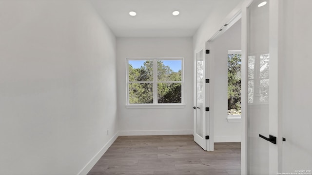 doorway to outside featuring baseboards, a wealth of natural light, and wood finished floors