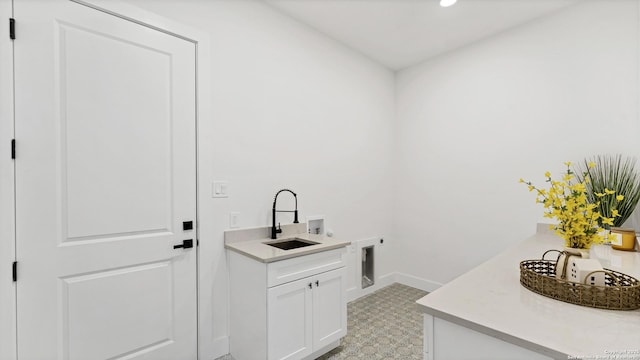 washroom featuring cabinet space, baseboards, hookup for an electric dryer, washer hookup, and a sink